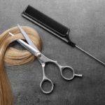 Stock image of a blonde hair lock, a pair of scissors and a tail comb