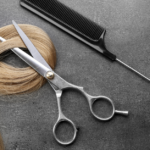 Stock image of a blonde hair lock, a pair of scissors and a tail comb